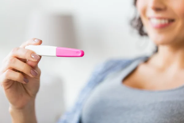 Close up of happy woman with home pregnancy test