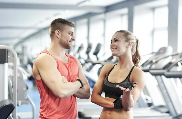 Smiling man and woman talking in gym