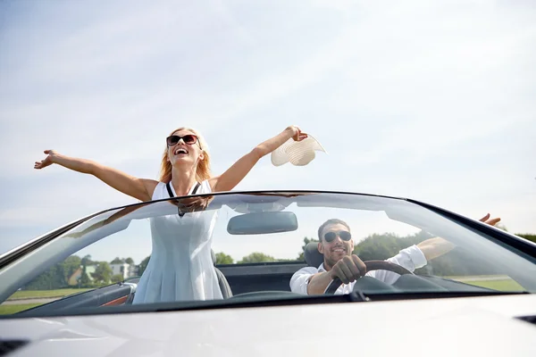 Happy man and woman driving in cabriolet car