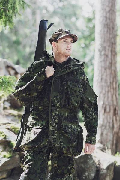 Young soldier or hunter with gun in forest