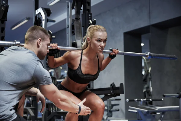 Man and woman with bar flexing muscles in gym