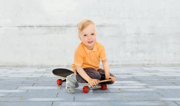 Happy little boy sitting on skateboard