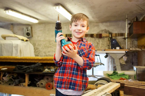 Happy little boy with drill at workshop