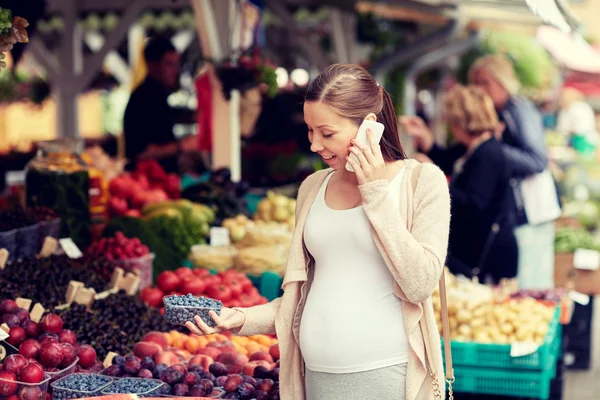 Pregnant woman calling on smartphone at market