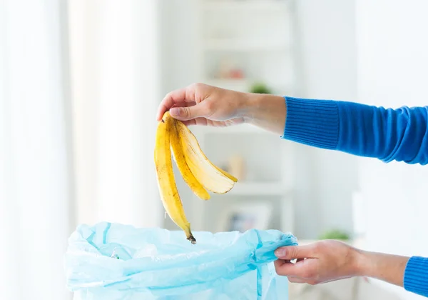 Close up of hand putting food waste to rubbish bag