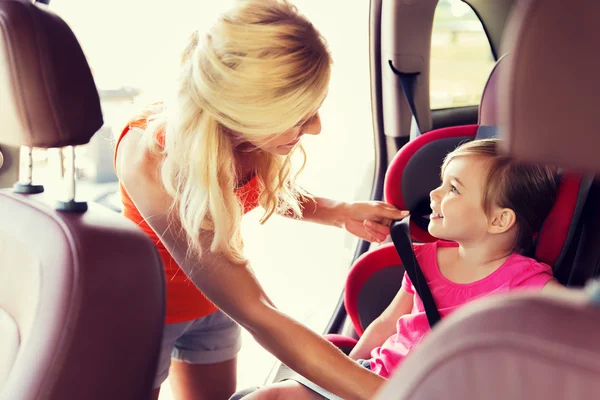 Happy mother fastening child with car seat belt