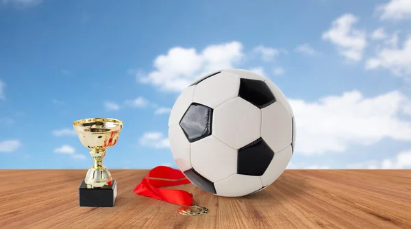 Close up of football ball, golden cup and medal