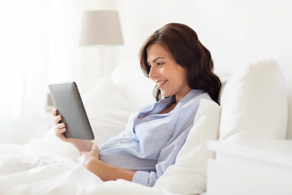 Happy pregnant woman with tablet pc at home