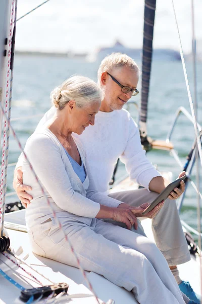Senior couple with tablet pc on sail boat or yacht
