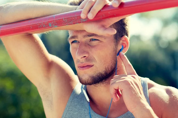 Young man with earphones and horizontal bar