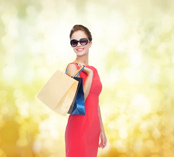 Smiling woman in red dress with shopping bags