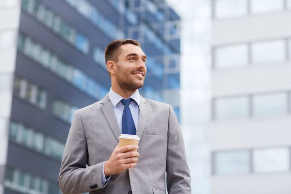 Young smiling businessman with paper cup outdoors