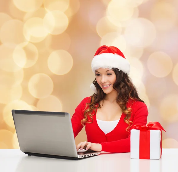 Smiling woman with gift box and laptop