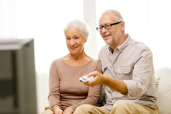 Happy senior couple watching tv at home