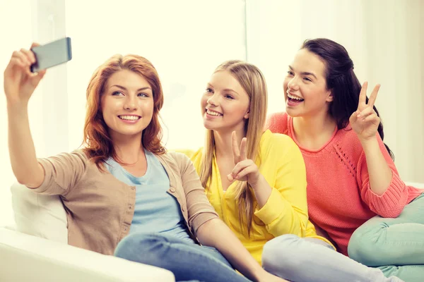 Smiling teenage girls with smartphone at home