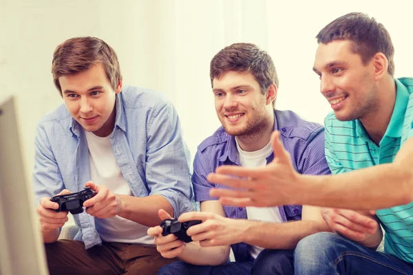 Smiling friends playing video games at home