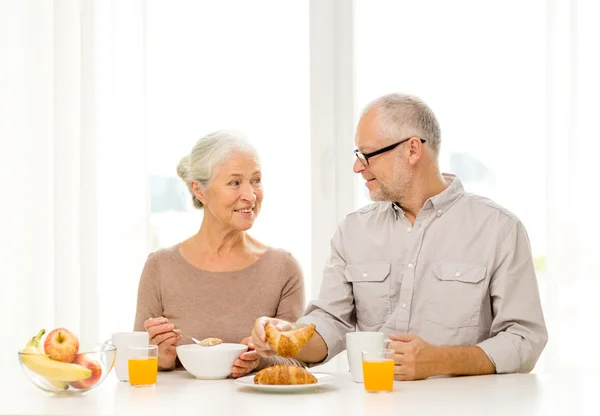 Happy senior couple having breakfast at home