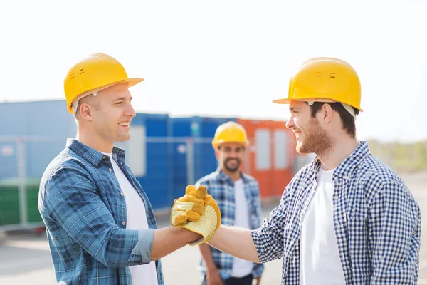 Group of smiling builders in hardhats outdoors