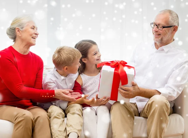 Smiling grandparents and grandchildren with gift