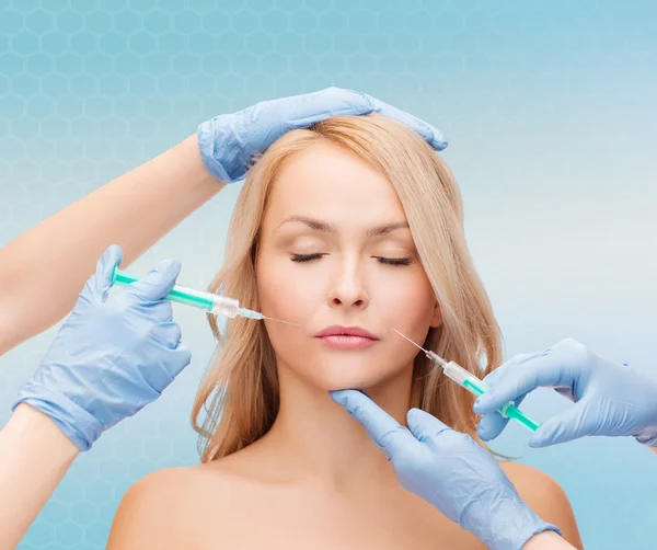 Woman face and beautician hands with syringes