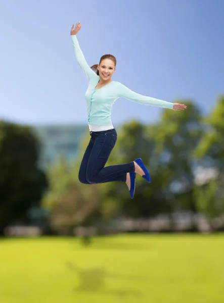 Smiling young woman jumping in air