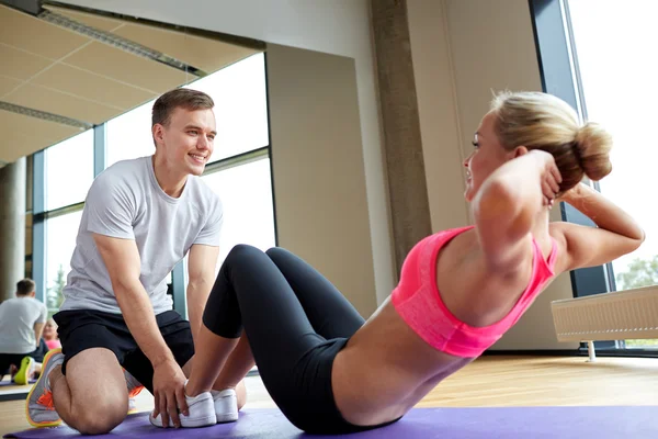 Woman with personal trainer doing sit ups in gym - Stock Image - Everypixel