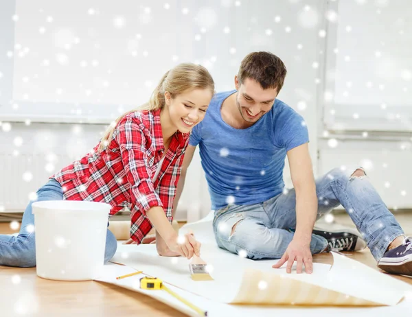 Smiling couple smearing wallpaper with glue