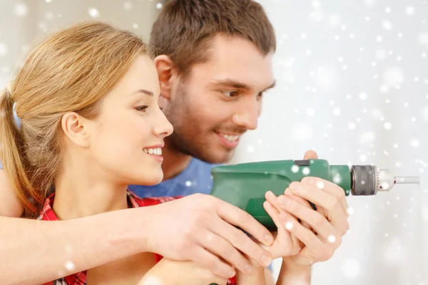 在家里的墙上钻孔的新人面带笑容 - 图库照片S