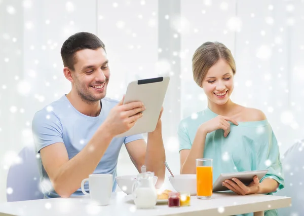 Smiling couple with tablet pc having breakfast