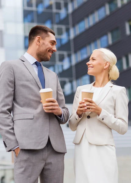 Smiling businessmen with paper cups outdoors