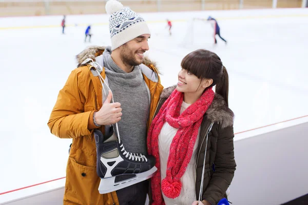 Happy couple with ice-skates on skating rink