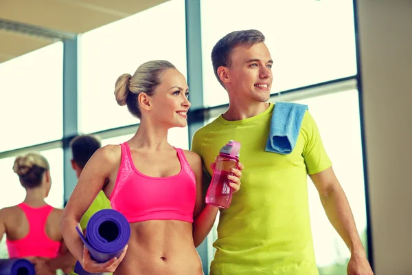 Smiling couple with water bottles in gym