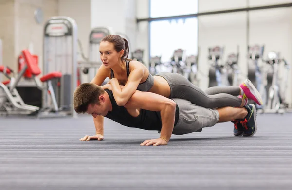 Smiling couple doing push-ups in the gym