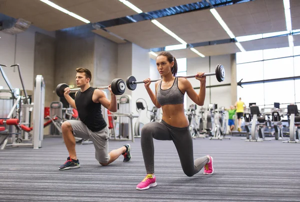 Young man and woman training with barbell in gym