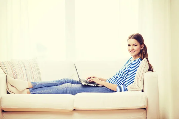 Smiling teenage girl with laptop computer at home