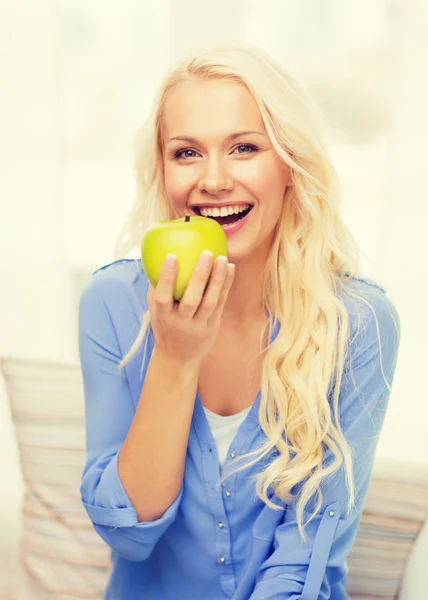 Smiling woman with green apple at home