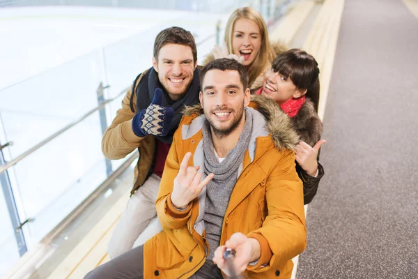 Happy friends taking selfie on skating rink