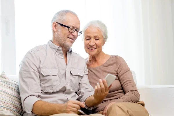 Happy senior couple with smartphone at home