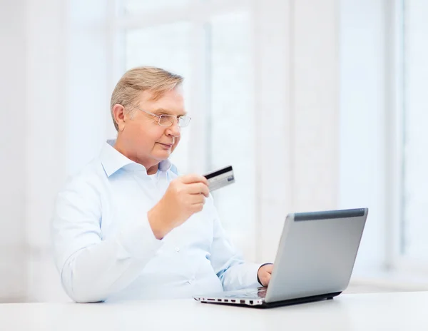 Old man with laptop and credit card at home