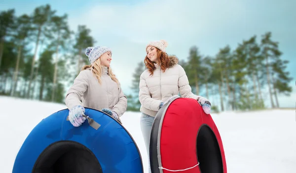 Happy girl friends with snow tubes outdoors