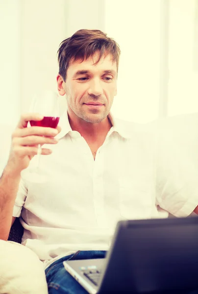 Man with laptop computer and glass of rose wine