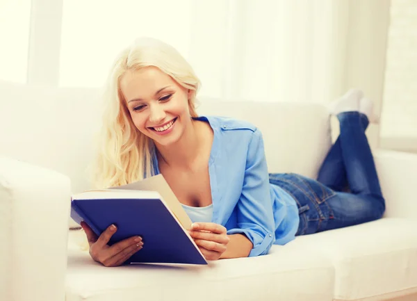 Smiling woman reading book and lying on couch