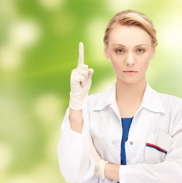 Smiling young female doctor pointing her finger up