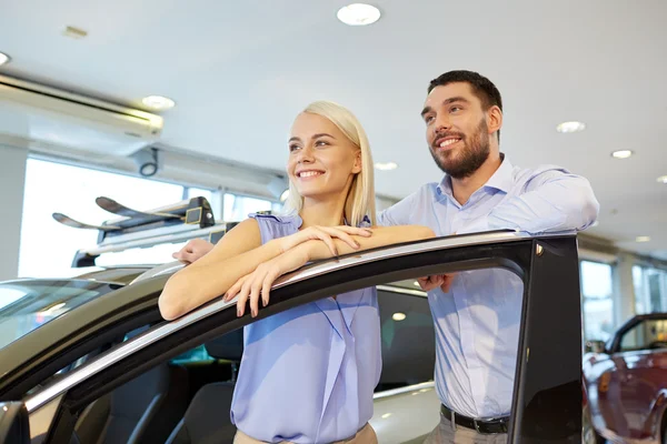 Happy couple buying car in auto show or salon