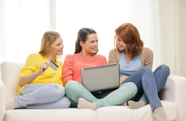 Smiling teenage girls with laptop and credit card