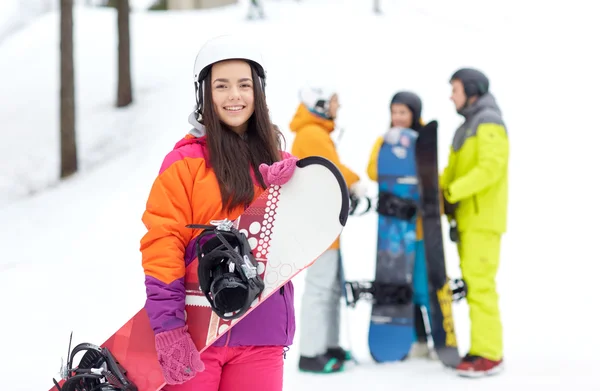 Happy friends in helmets with snowboards