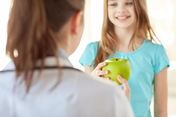 Close up of doctor giving apple to happy girl