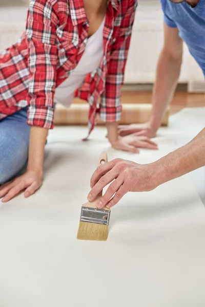 Close up of couple smearing wallpaper with glue