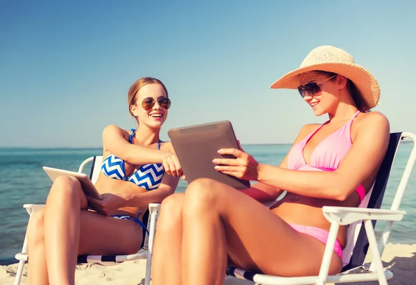 Smiling women with tablets pc computers on beach