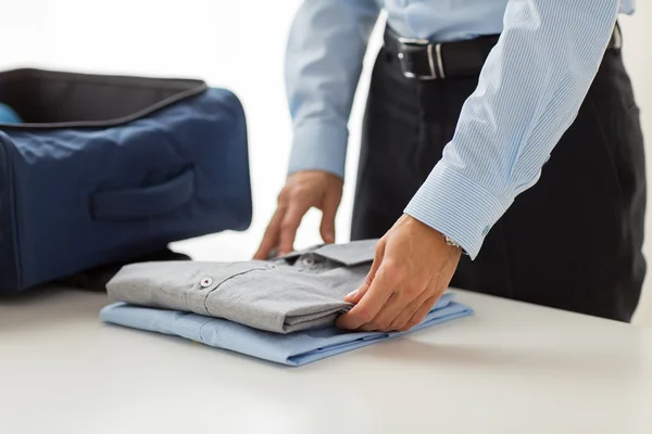 Businessman packing clothes into travel bag